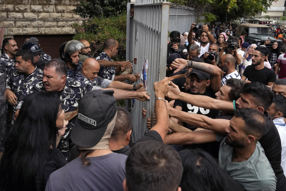 Protesters try to remove a gate to the Justice Palace during a demonstration demanding the release of two people arrested last week during a bank robbery, in Beirut, Lebanon, Monday, Sept. 19, 2022. Anger with local lenders who have been imposing informal capital controls including limits on ATM withdrawals for nearly three years increased in recent weeks, with some depositors storming bank branches and taking their trapped savings by force. (AP Photo/Bilal Hussein)