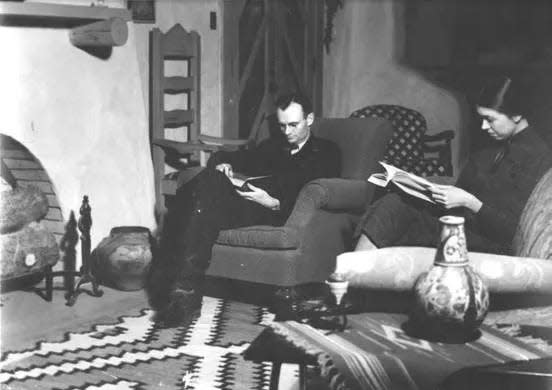 William Curry Holden and his wife read by the fireplace in their home.