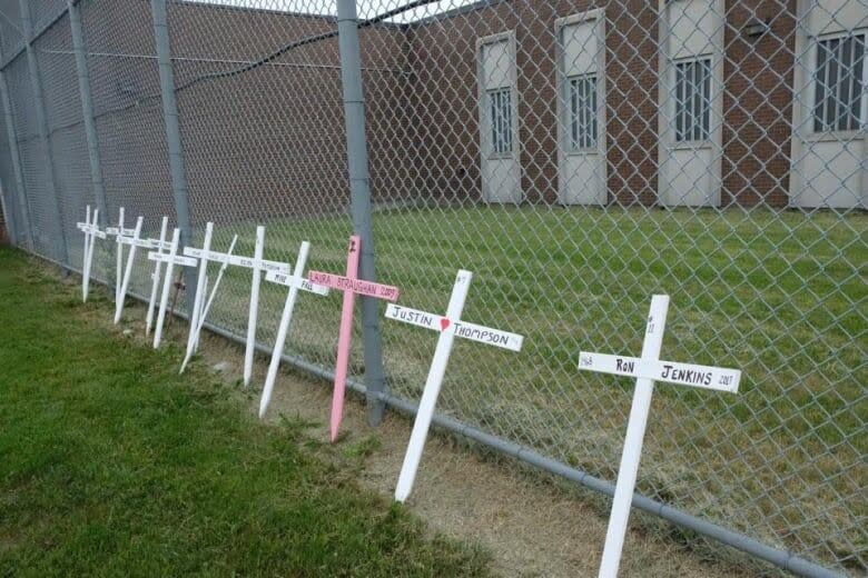 Crosses rest against a fence at London's Elgin-Middlesex Detention Centre in 2019 with the names of inmates who have died at the jail. 