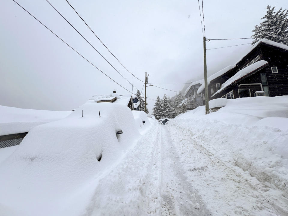 Windshield wipers and the side mirror are visible from one of the vehicles buried under snow along a steep street in downtown Juneau on Tuesday, Jan. 23, 2024. Juneau has received more than 55 inches of snow so far in January, far above the normal level of 24.5 inches, according to the National Weather Service. (AP Photo/Becky Bohrer)