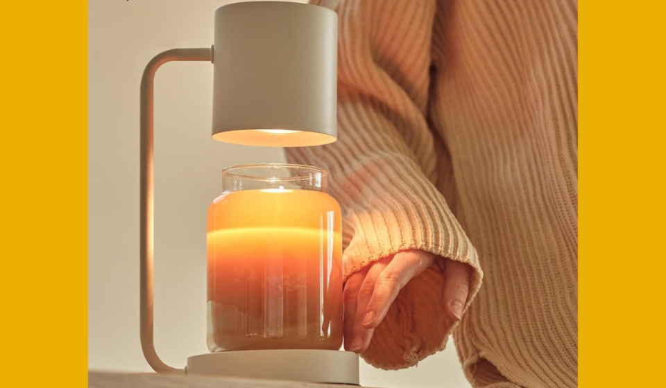 someone's hand touching the side of a candle that's under the white candle warmer