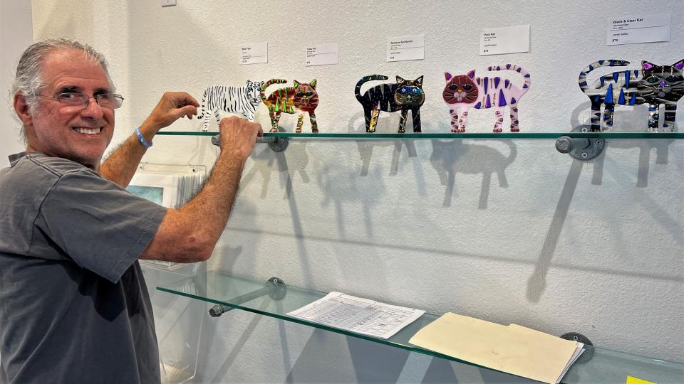 Artist Jamille Haddad fills a shelf with his glass art at the Studios of Cocoa Beach.