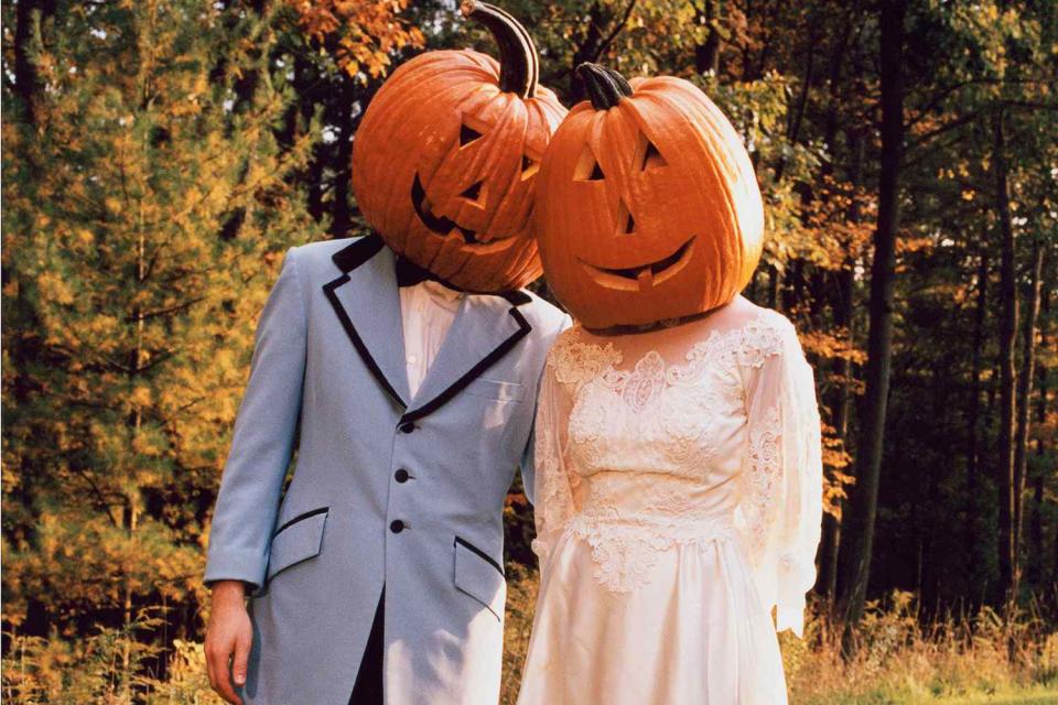 <p>Getty</p> A bride and groom pictured with pumpkins on their heads