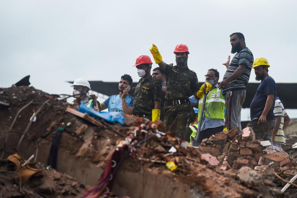 Rescue workers search for survivors in the rubble of a collapsed five-storey apartment building in Mahad. (Photo by PUNIT PARANJPE/AFP via Getty Images)