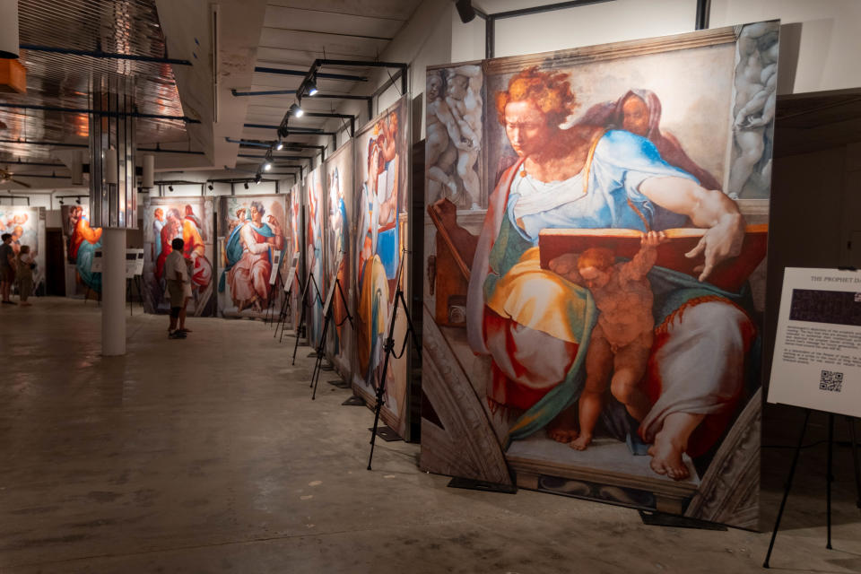 Patrons look over  some  of the 34 paintings that were reproduced for Michelangelo's Sistine Chapel: The Exhibition at  Arts in the Sunset in Amarillo.