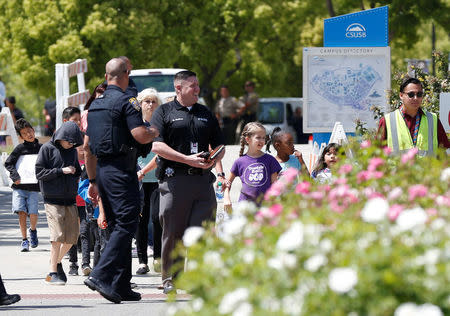 REFILE -- CORRECTING TYPO -- Police officers escort students from a campus of California State University - San Bernardino, where they were evacuated after a shooting at North Park Elementary School, to be reunited with their parents in San Bernardino, California, U.S. April 10, 2017. REUTERS/Mario Anzuoni