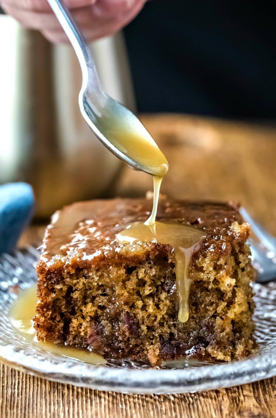 Drizzling caramel onto sticky toffee pudding cake.