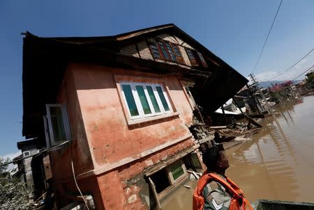 An Indian army soldier sits in a rescue boat past a destroyed house as he and others search for stranded flood victims in Srinagar September 13, 2014. REUTERS/Adnan Abidi