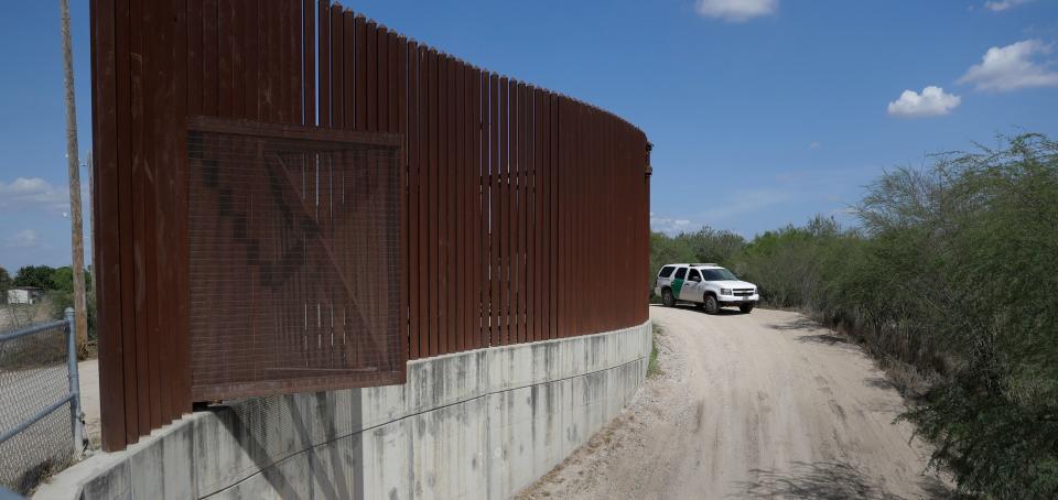 A Customs and Border Patrol vehicle passes along a section of border levee wall in Hidalgo, Texas.