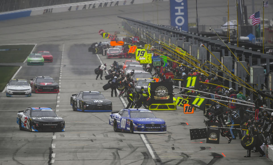 Tyler Reddick (20), Jeffrey Earnhardt (18), and Cole Cluster (00) pull to the front while making a pit stop with other drivers during a NASCAR Xfinity auto race at Atlanta Motor Speedway, Saturday, Feb. 23, 2019, in Hampton, Ga. (AP Photo/John Amis)