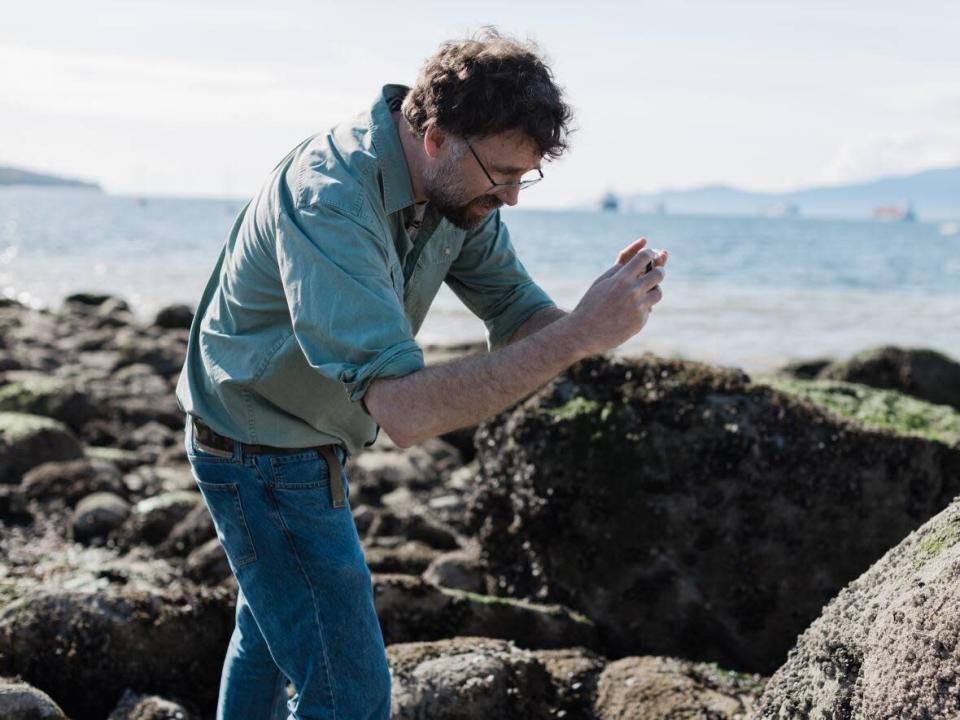 UBC marine biologist Chris Harley takes comparison photos of spots along Vancouver&#39;s Kits Beach, where he initially found thousands of shellfish that cooked to death during a heat dome in 2021. (Gian Paolo Mendoza/CBC - image credit)
