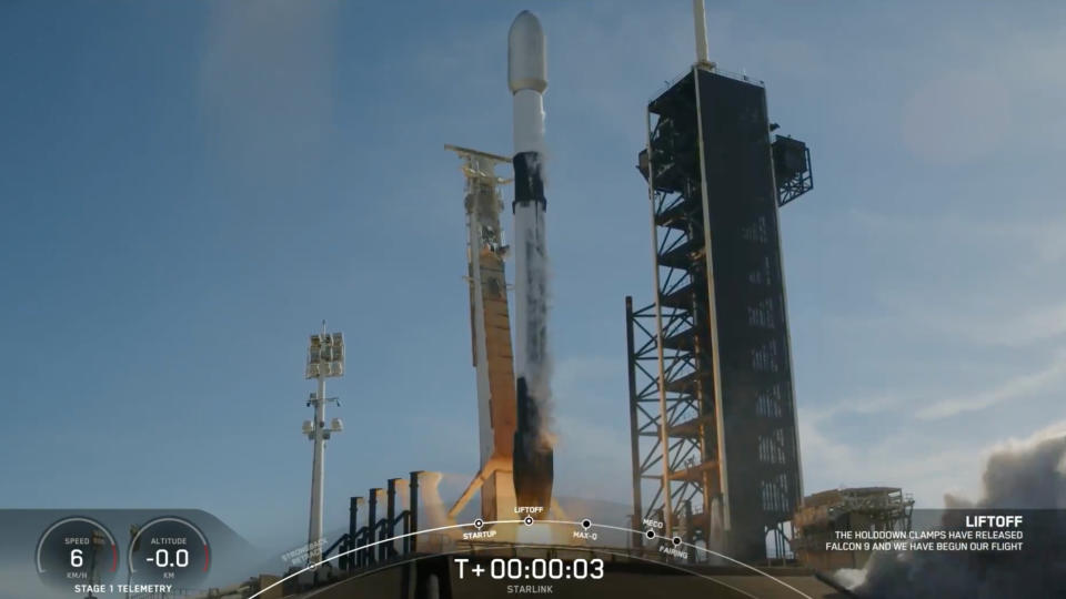 a black-and-white spacex falcon 9 rocket launches into a blue sky.