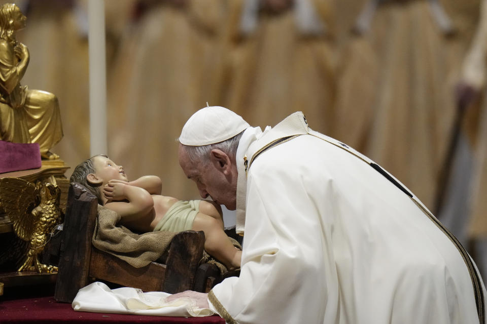 Pope Francis kisses a statue of Baby Jesus as he celebrates Christmas Eve Mass, at St. Peter's Basilica, at the Vatican, Friday Dec. 24, 2021. (AP Photo/Alessandra Tarantino)