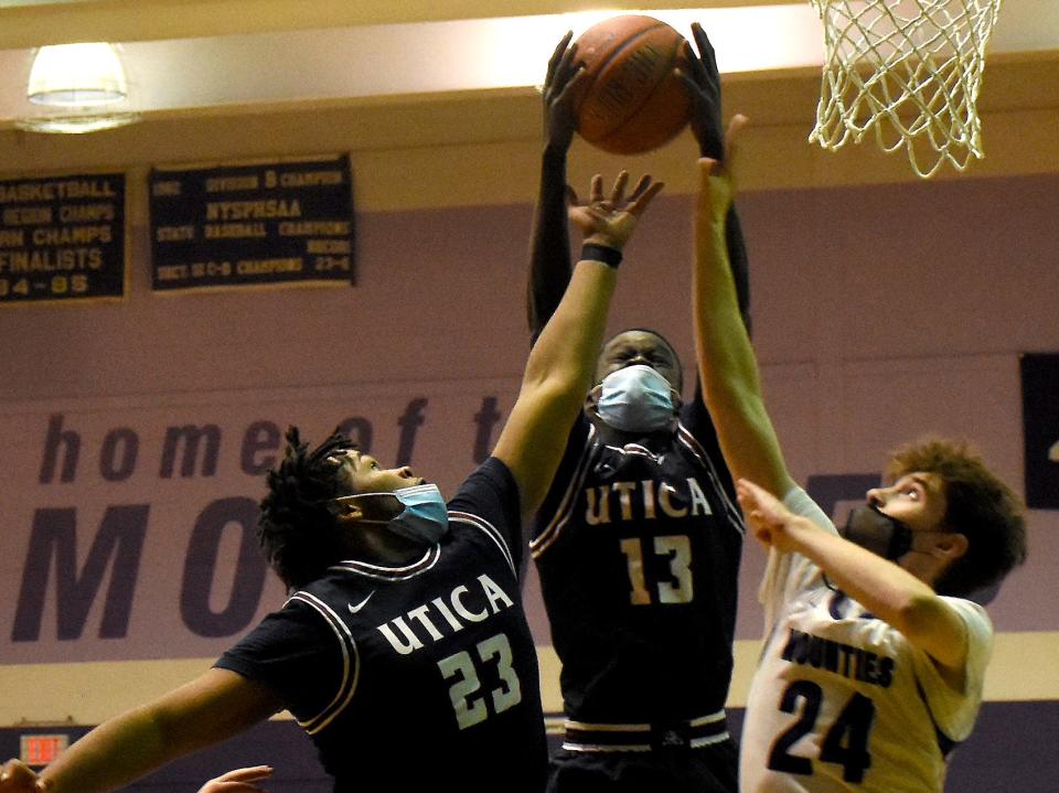 Wol Machteng (13) grabs an offensive rebound between Utica Academy of Science teammate Stephen Brown (23) and Little Falls Mountie Brayton Mosher (24) during the third quarter of Tuesday's game.