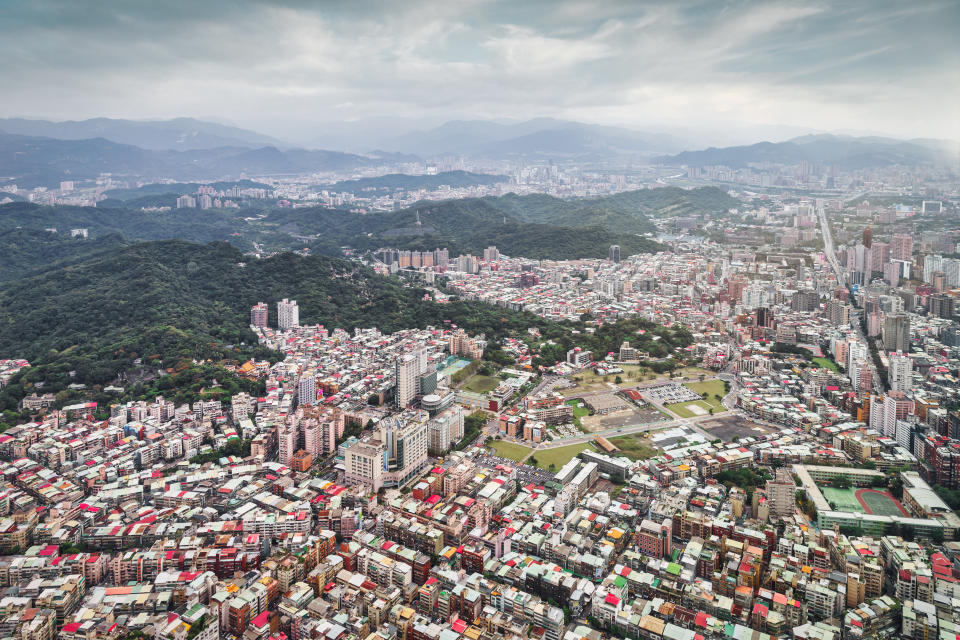 Taiwan Taipei Urban City View. Aerial view to Downtown Taipei Urban Sprawl under moody dramatic fog and rainy cloudscape. Green hill range and mountains surrounding Taipei City in the background. Wide Angle City View. Taipei City, Taiwan, East Asia, Asia