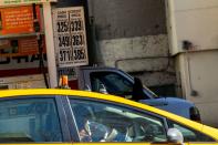 A cab driver wears plastic gloves after fueling his car in a gas station while gasoline price has been declined due to coronavirus disease (COVID-19) in New York