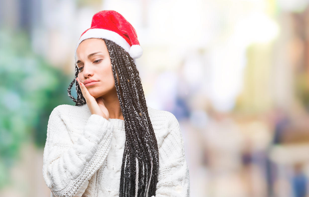 Young braided hair african american girl wearing christmas hat over isolated background thinking looking tired and bored with depression problems with crossed arms.