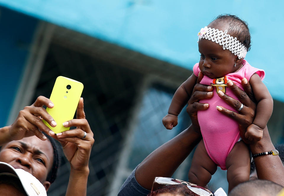 A fateful holds a child as Pope Francis greets people in a neighbourhood in Cartagena