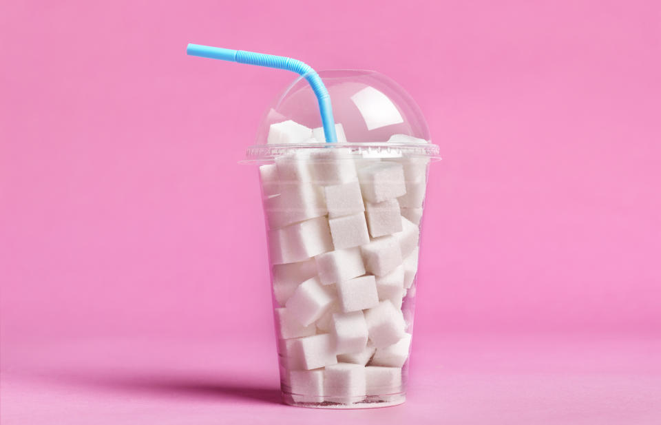 Plastic cup filled with sugar cubes, straw poking out, concept for high sugar content in drinks