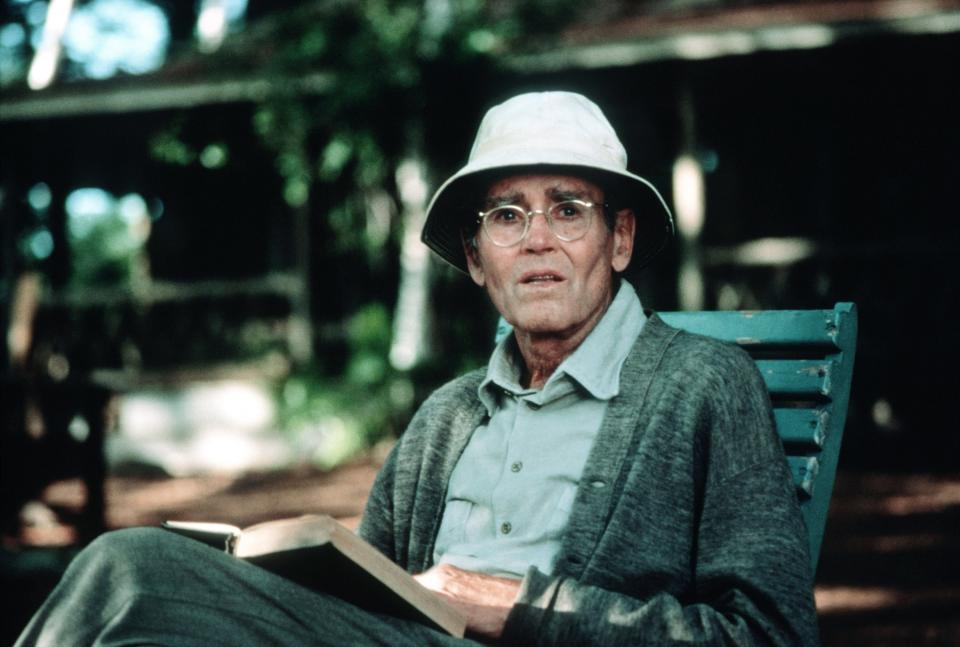 An older gentleman sitting in a chair and reading a book