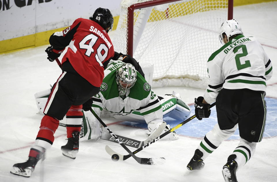 Dallas Stars goaltender Anton Khudobin (35) and defenseman Jamie Oleksiak (2) attempt to get the puck away from Ottawa Senators right wing Scott Sabourin (49) during the first period of an NHL hockey game Sunday, Feb. 16, 2020, in Ottawa, Ontario. (Justin Tang/The Canadian Press via AP)