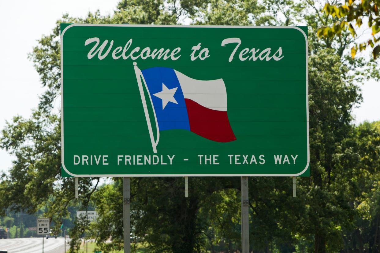 A highway sign saying "Welcome to Texas" with a Texas state flag.