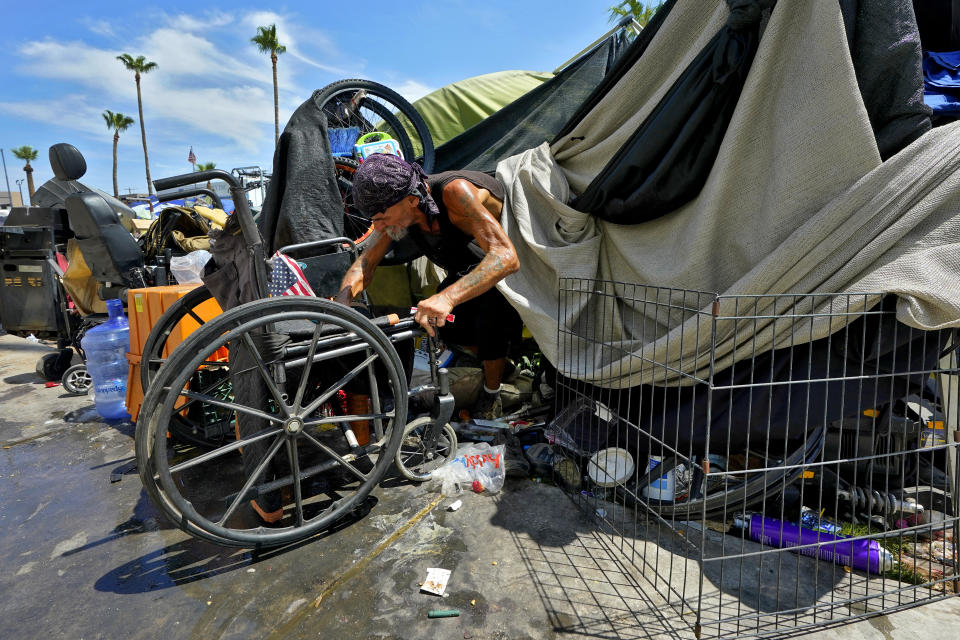 Charles Sanders, 59, climbs out of his tent inside the homeless encampment called "The Zone," Friday, July 14, 2023, in downtown Phoenix. Sanders, from Denver, has been spending the days at the Justa Center, a day center for homeless people 55 years and older in the downtown area. Several dozen people stop by daily for cold water, a meal, a shower and an electrical outlet to charge a mobile phone. (AP Photo/Matt York)