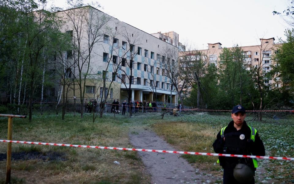 Emergency services personnel near a cordon after a Russian missile strike in Kyiv - VALENTYN OGIRENKO/REUTERS