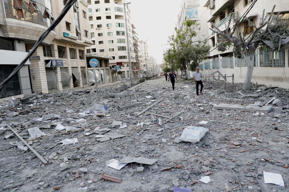 FILE - In this May 17, 2021, file photo, people inspect the rubble of a destroyed commercial building and Gaza health care clinic following an Israeli airstrike on the upper floors of a commercial building near the Health Ministry in Gaza City. The Gaza Strip's already feeble health system is being brought to its knees by the fourth war in just over a decade. (AP Photo/Adel Hana, File)