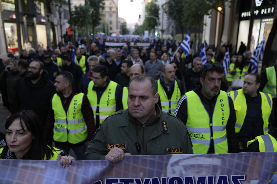 A riot policeman holds a banner during a protest by uniformed officers in Athens, Greece, Monday, Dec. 18, 2023. About 1,500 people took part in the rally, organized by police, firefighters and coast guard unions in response to the non-legalization of their profession as hazardous. (AP Photo/Thanassis Stavrakis)