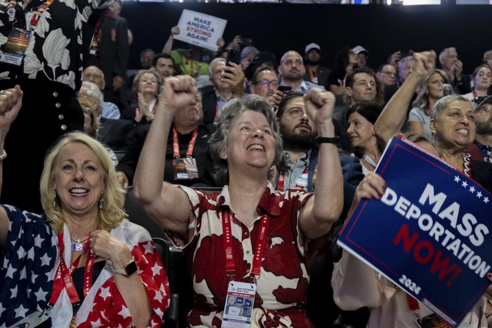 A photograph of mature women in patriotic clothing cheering and holding a sign that says mass deportation now at the republican national convention in 2024