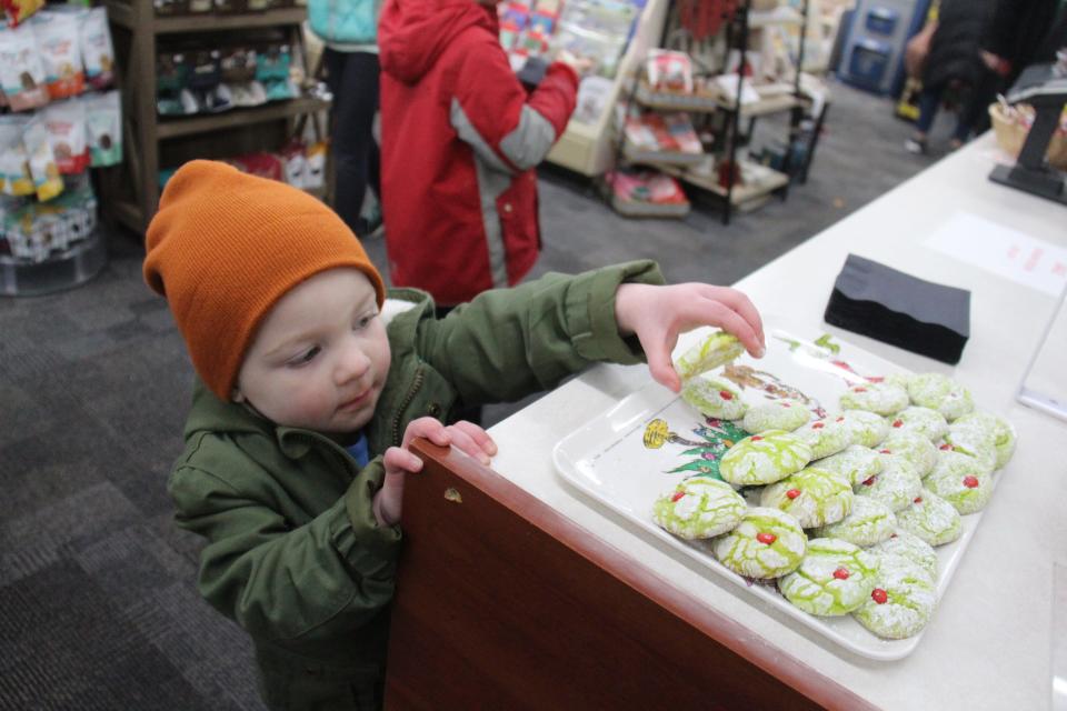 Ellie Cave, 3, grabs a Grinch cookie at Adel HealthMart during the Sip and Sample event as part of the Hometown Holiday Celebration on Friday, Dec. 2, 2022, in Adel.