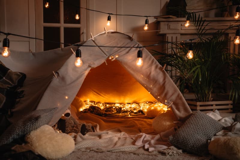 A tent in the living room. String lights are hung for a cozy atmosphere