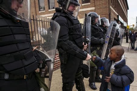 A young boy greets police officers in riot gear during a march in Baltimore, Maryland May 1, 2015 following the decision to charge six Baltimore police officers -- including one with murder -- in the death of Freddie Gray, a black man who was arrested and suffered a fatal neck injury while riding in a moving police van, the city's chief prosecutor said on Friday. REUTERS/Lucas Jackson