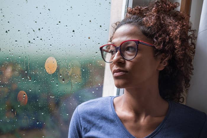 A woman looking out the window at the rain