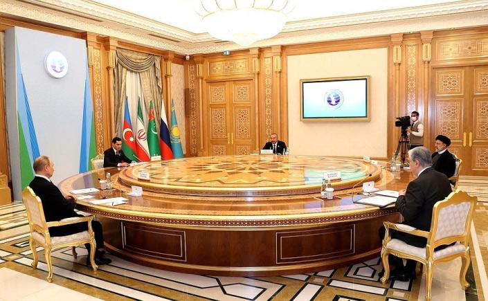 An image of Putin and the presidents of Azerbaijan, Iran, Kazakhstan, and Turkmenistan sitting around a huge round table.