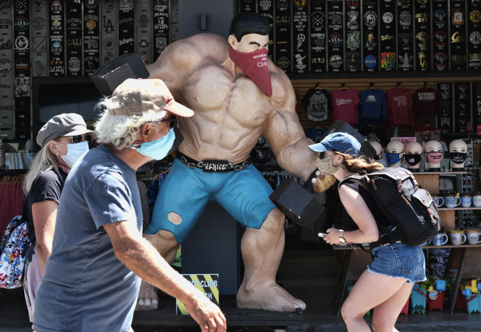 Pedestrians wearing masks to protect from the coronavirus walk along the strand at the Muscle beach section of Venice in Los Angeles on Friday, July 3, 2020. California's governor is urging people to wear masks and skip Fourth of July family gatherings as the state's coronavirus tally rises. All L.A. County beaches are closed from July 3 through July 6, to prevent dangerous crowding. Rates of COVID-19 infections and hospitalizations have soared in the past two weeks after falling last month. (AP Photo/Richard Vogel)