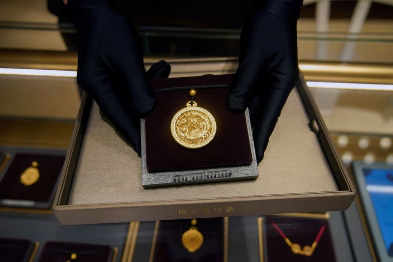 A salesperson poses with Heritage Gold jewellery at jeweller Chow Tai Fook’s retail store in Shanghai