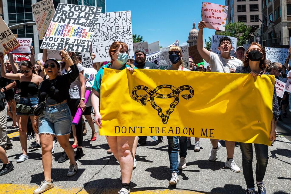 Protesters hold up signs as they march down Congress Ave at a protest outside the Texas state capitol on May 29, 2021 in Austin, Texas. Thousands of protesters came out in response to a new bill outlawing abortions after a fetal heartbeat is detected signed on Wednesday by Texas Governor Greg Abbot.