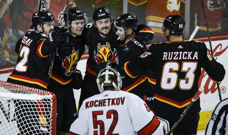 Carolina Hurricanes goalie Pyotr Kochetkov (52) looks on as Calgary Flames forward Connor Zary (47) celebrates with teammates after scoring during third-period NHL hockey game action in Calgary, Alberta, Thursday, Dec. 7, 2023. (Jeff McIntosh/The Canadian Press via AP)