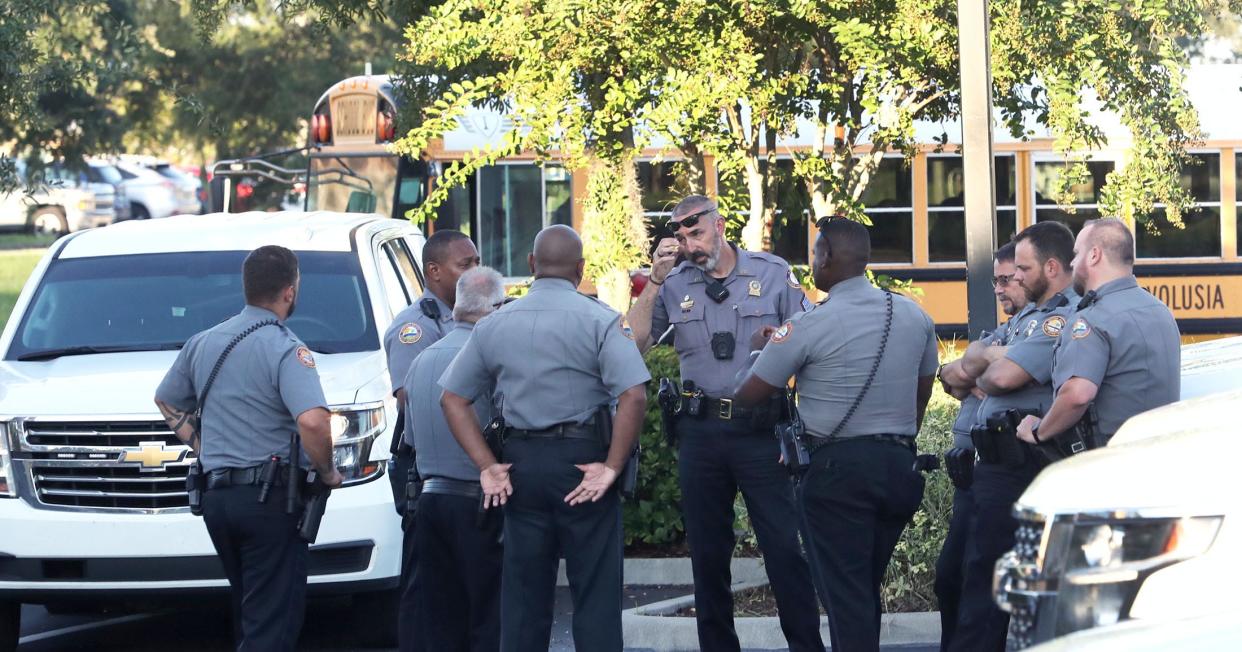 Daytona Beach Police officers standby in a parking lot just east of Mainland High School as a school bus rolls by, Monday morning, Sept. 12, 2022, part of a large presence of officers on the campus following Friday's unfounded report of a shooting at the school.