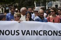 People hold a banner reading "We will overcome" as they take part in a silent march on July 30, 2016 in Lyon following the fatal attack on a French priest