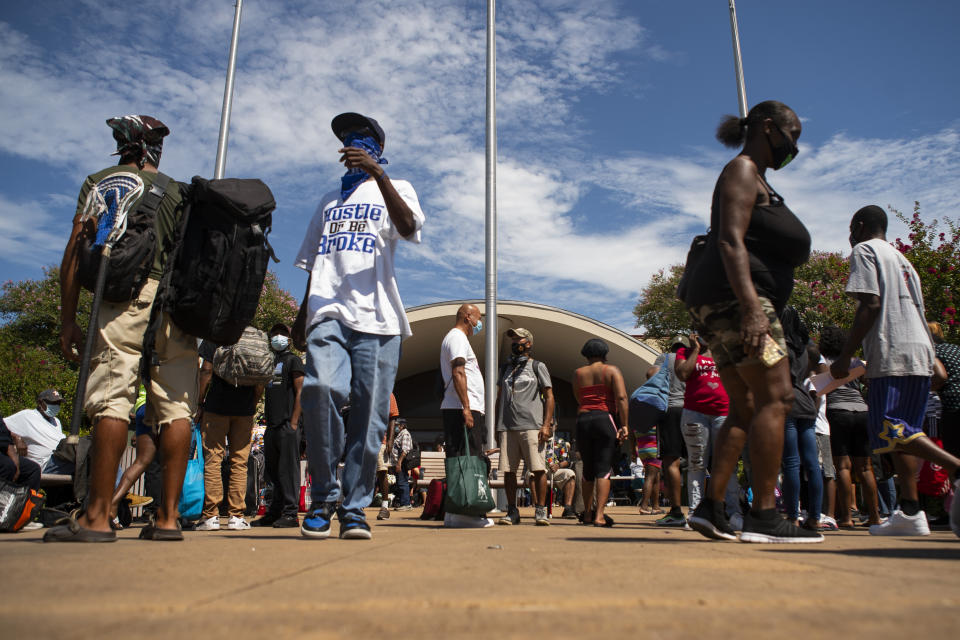 La gente espera en fila ante las oficinas del departamento de vivienda de Galveston para subir a autobuses que los evacuarán desde Galveston Island a Austin antes de la llegada del huracán Laura, el 25 de agosto de 2020, en Galveston, Texas. ( Mark Mulligan/Houston Chronicle via AP)