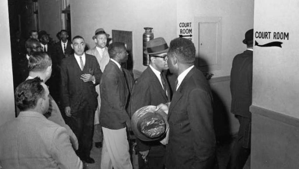 Lawyers proceed into the court room at the Richland County Court House for the case against James Edwards Jr., et al. Edwards and others were arrested for breach of peace following civil rights demonstrations they conducted at the S.C. State House on March 2, 1961. Pictured here are several defendants along with attorneys Matthew Perry, wearing glasses, and Lincoln C. Jenkins, in hat and overcoat. State N.A.A.C.P president J. Arthur Brown, with hand raised to his breast pocket, is also in the group.