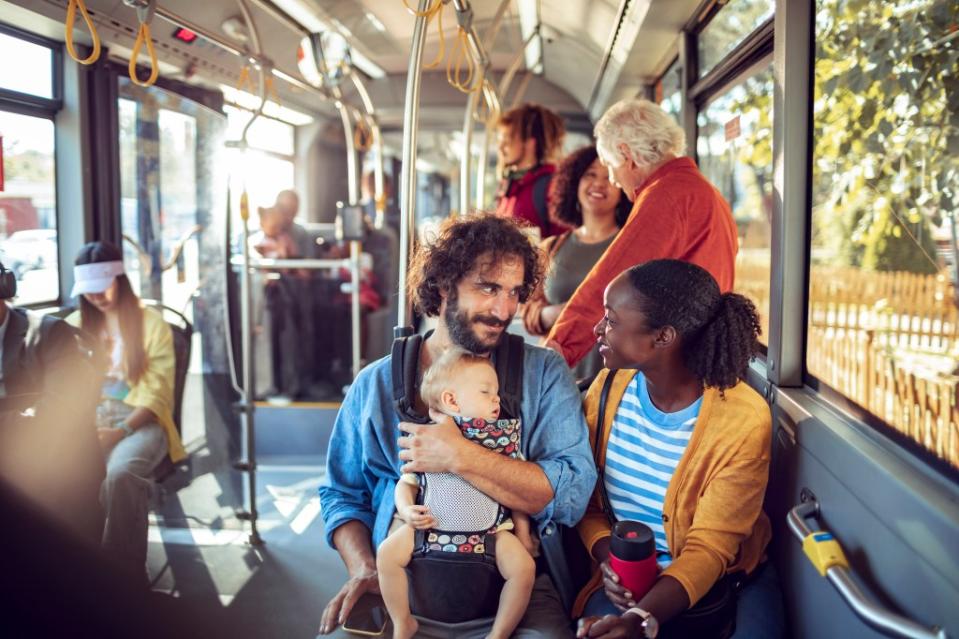 Family with kid in a baby carrier in a bus via GettyImages