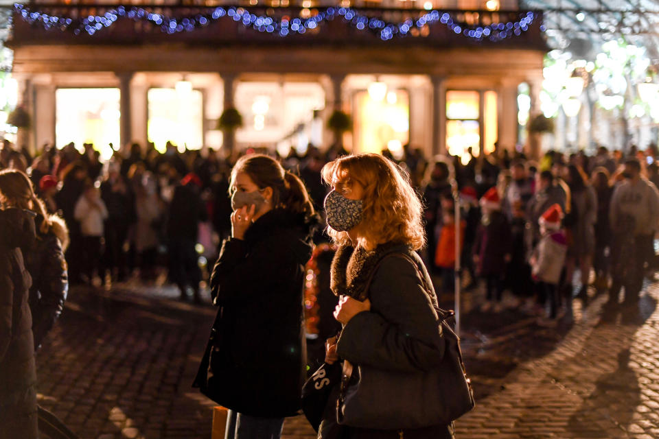 People wear face masks as they walk in Covent Garden, in London, Saturday, Dec. 12, 2020.