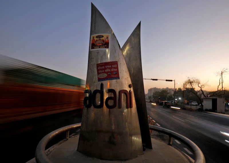 FILE PHOTO: Traffic moves past the logo of the Adani Group installed at a roundabout on the ring road in Ahmedabad