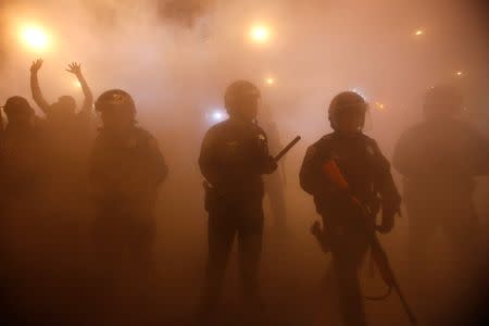 Police officers walk through smoke from a bonfire during a street celebration in the Mission District, in San Francisco, California October 29, 2014. REUTERS/Stephen Lam