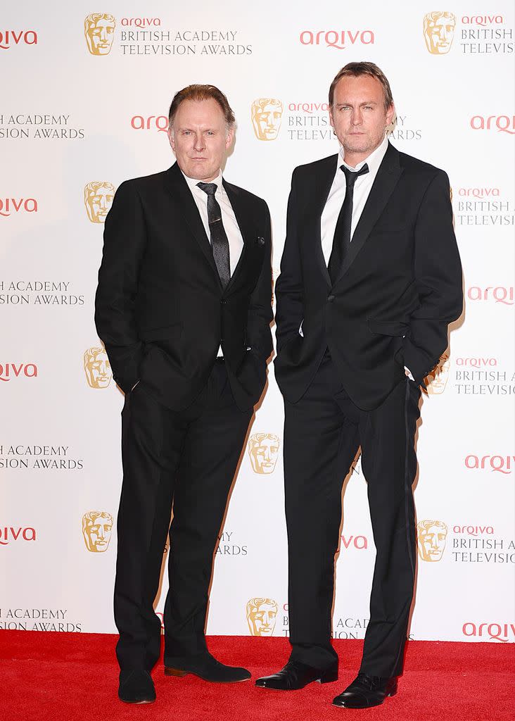 Robert and Philip Glenister stand on red carpet at BAFTAs in 2012