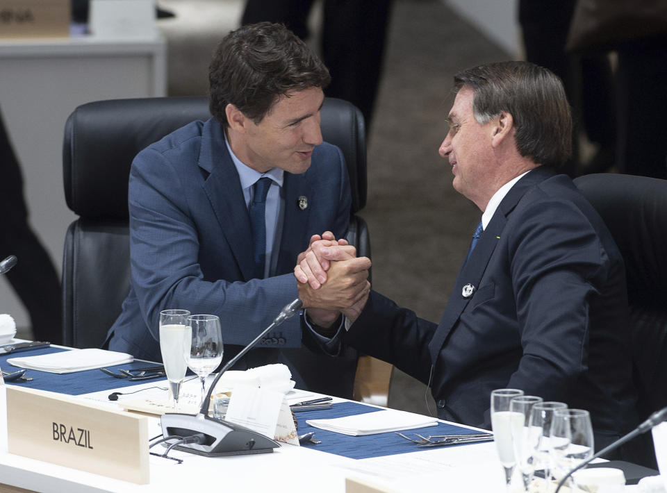 FILE - In this Friday, June 28, 2019 photo, Canadian Prime Minister Justin Trudeau shakes hands with Brazilian President Jair Bolsonaro before the start of a plenary session at the G20 Summit in Osaka, Japan. On Friday, July 5, 2019, The Associated Press reported on a video circulating online which was deceptively edited to assert incorrectly that Trudeau was ignored by Bolsonaro at the event. (Adrian Wyld/The Canadian Press via AP)